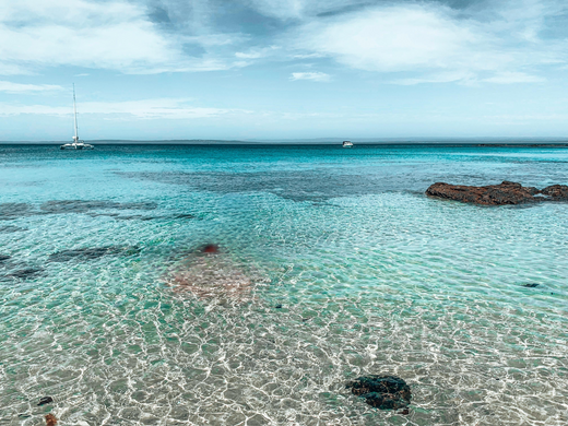A luxurious setup featuring champagne and a charcuterie board on a floating pontoon at Tangalooma, surrounded by crystal-clear waters and a serene coastal backdrop